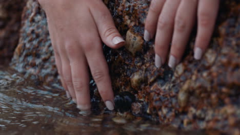 Cerrar-Las-Manos-Tocando-Roca-Húmeda-Corriente-Refrescante-Que-Fluye-Río-Fresco-Salpicando-El-Concepto-De-Sostenibilidad