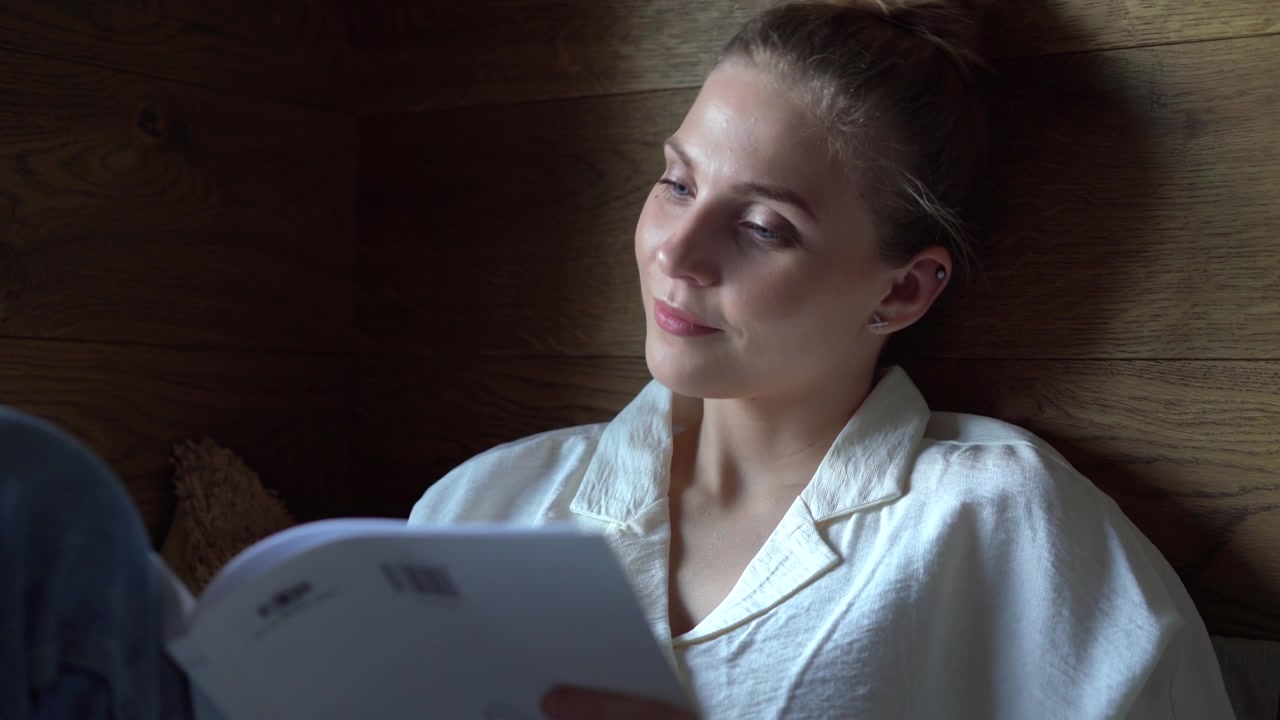 Young Woman Reading a Book in a Cozy Wooden Interior