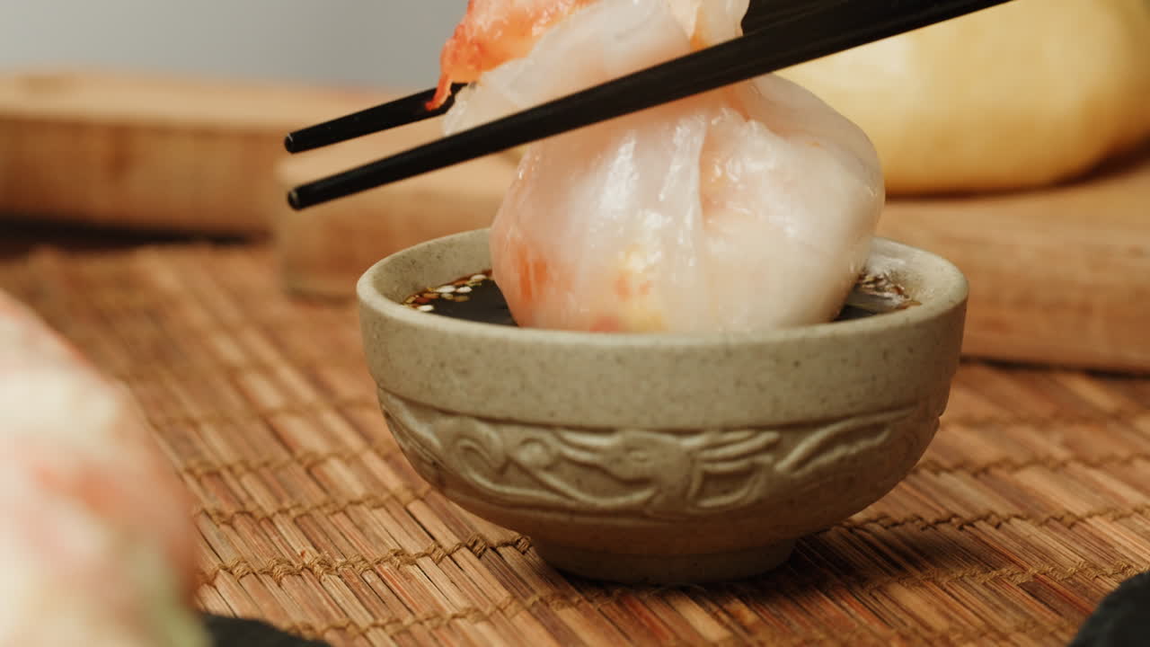 Dipping Asian Dumpling into Soy Sauce with Chopsticks