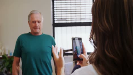 fisioterapeuta tomando una foto de un hombre mayor con teléfono móvil 4k