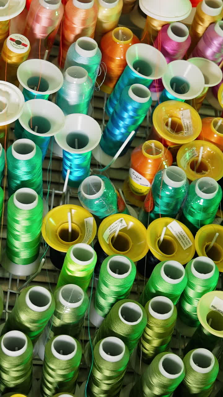 Background of colorful spools.Rows spools of thread of different colors for the sewing machine. Bright colors of threads on the table. Vertical video