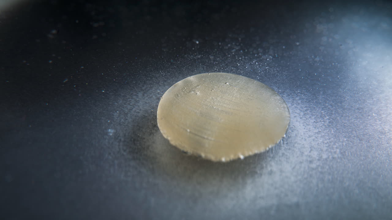 Dissolving pill in liquid, viewed in timelapse, showing gradual dissolution process
