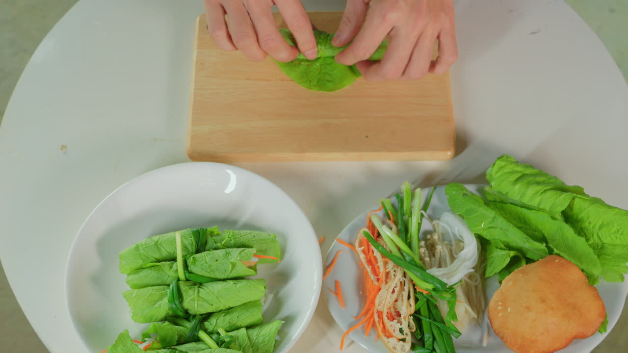 hadn't chef top down view while preparing vegan spring rolls rolling a salad leaf with vegetable inside for healthy food