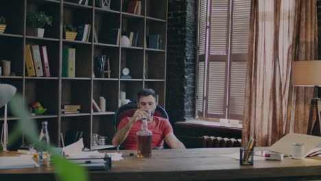 business man sitting in office chair and drinking whiskey