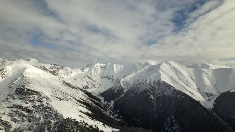 Snow-capped-Fagaras-Mountains-under-a-clear-blue-sky,-panoramic-aerial-shot