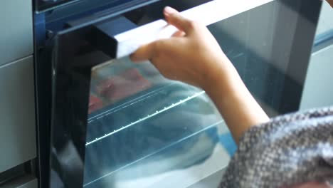 woman placing a baking tray of salmon in an oven