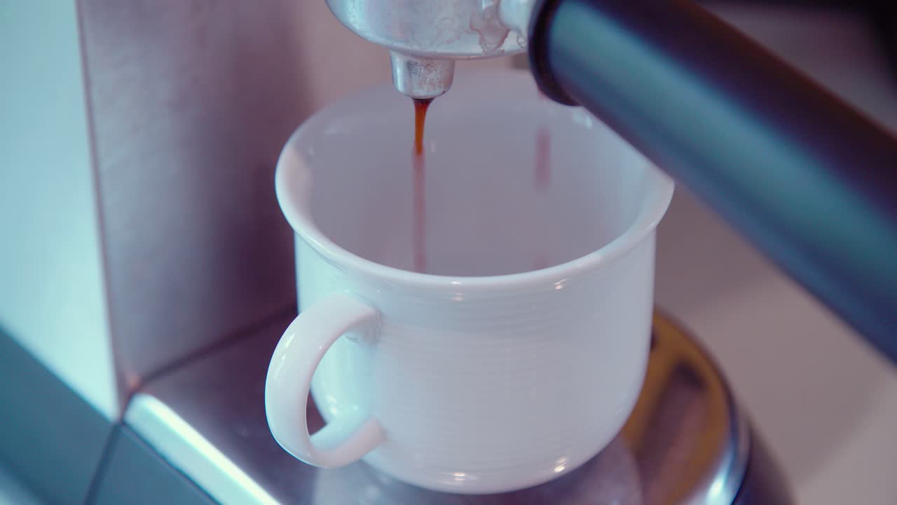 taza de café bajo la máquina de espresso que comienza a verter