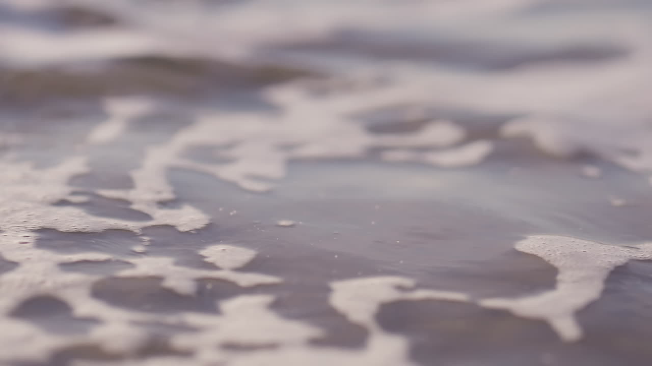 olas del mar corriendo en la playa durante la puesta de sol