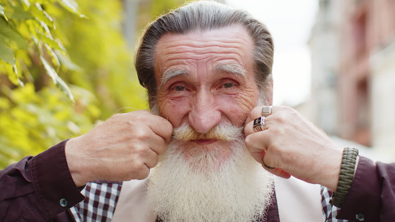 Happy mature old man smiling looking away resting good news feel satisfied fixing mustache in city