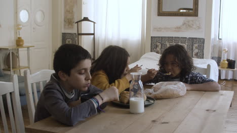 Medium-shot-of-kids-sitting-at-table-and-eating.