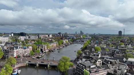 the drone is flying sideways rotating above the amstel canal with a overview of the city amsterdam in the netherlands aerial footage 4k