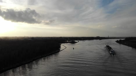 empty coupled barge sailing with two engines on the dutch river oude maas on a sunny partly cloudy day