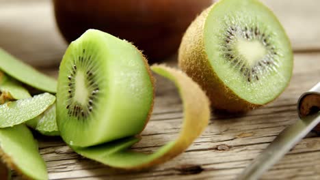 media sección y cáscara de kiwi en una mesa de madera