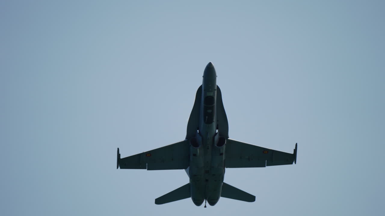 Military jet in midair banking maneuver with visible motion blur indicating high speed