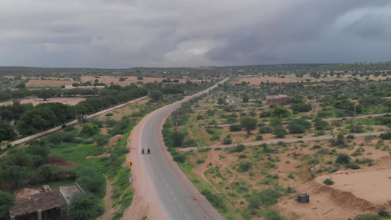 drone toma una foto aérea de los dos motociclistas conduciendo su bicicleta en la carretera aislada de tharparkar ubicada en la provincia de sindh de pakistán