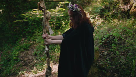 young druid girl sits in a forest and contemplates her staff medium shot