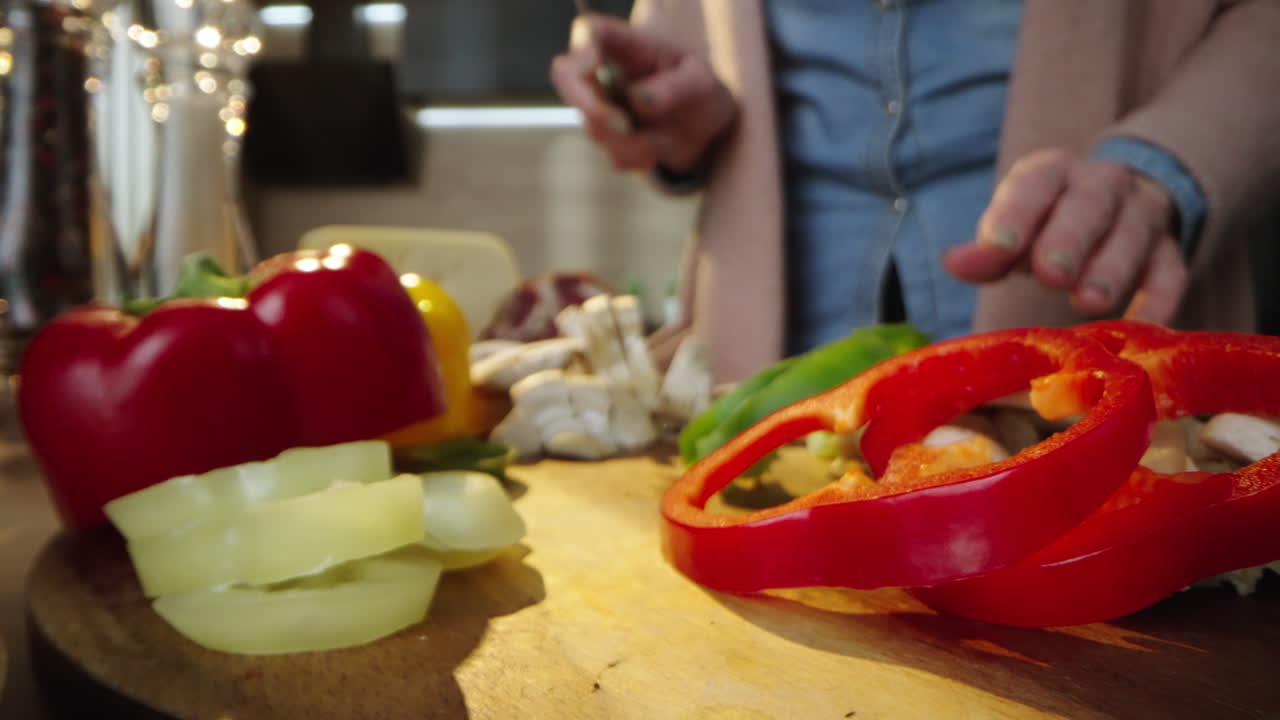 Person cutting colorful peppers on wooden board