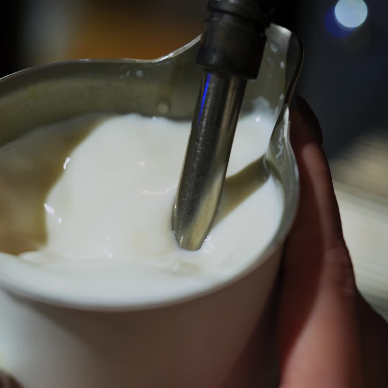 Hot milk pouring from coffee machine. Making fresh coffee with milk. Process of cappuccino preparation. Close-up.