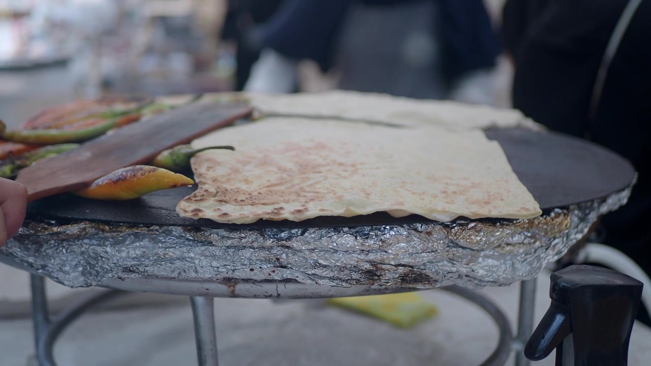 Street Food Vendor Cooking Flatbread and Peppers on a Griddle