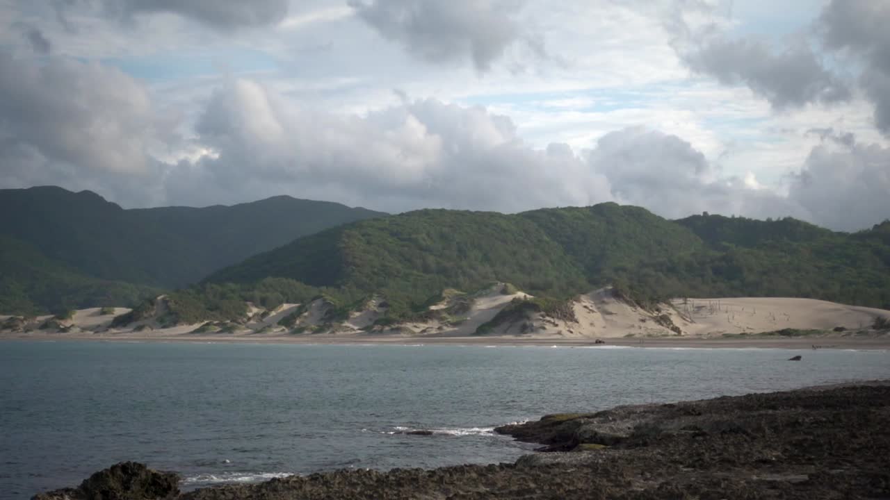 녹색 범위와 구름이 있는 해변의 모래 산