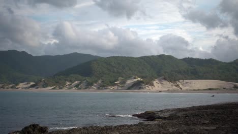 Sandy-mountains-on-seaside-with-green-coverage-and-clouds
