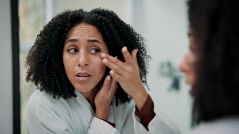 woman examining her skin in the mirror