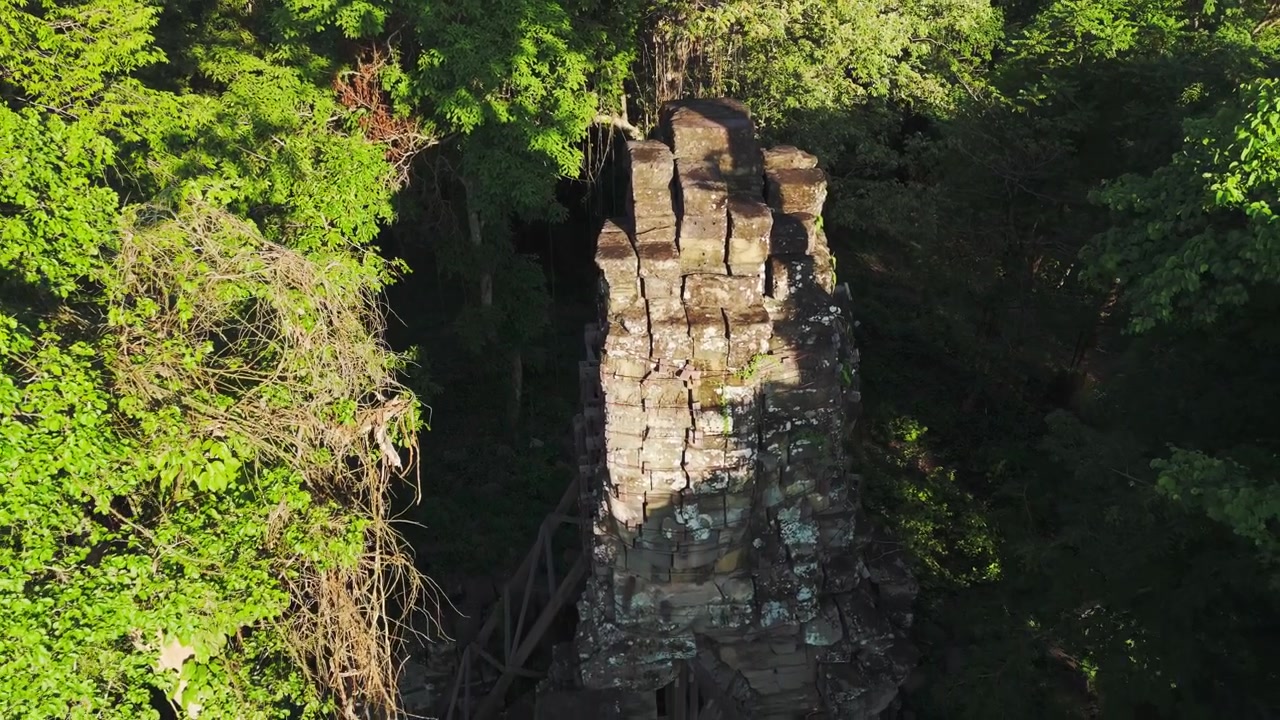 Enormi volti di arenaria su strutture di templi nascosti sepolti in un complesso nella giungla remota vicino al confine thailandese. Rivelazione aerea con drone dell'ambiente naturale circostante.