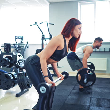 muscular bearded man having workout together with beautiful woman. healthy man and a woman training with heavy barbells in sports center.
