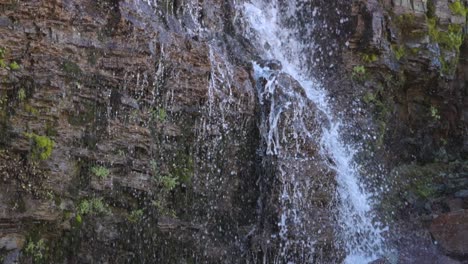 Cascada-Al-Borde-De-La-Carretera-En-El-Parque-Nacional-De-Los-Glaciares,-En-120-Fps-Con-Agua-Salpicada-En-Las-Rocas-De-Cerca