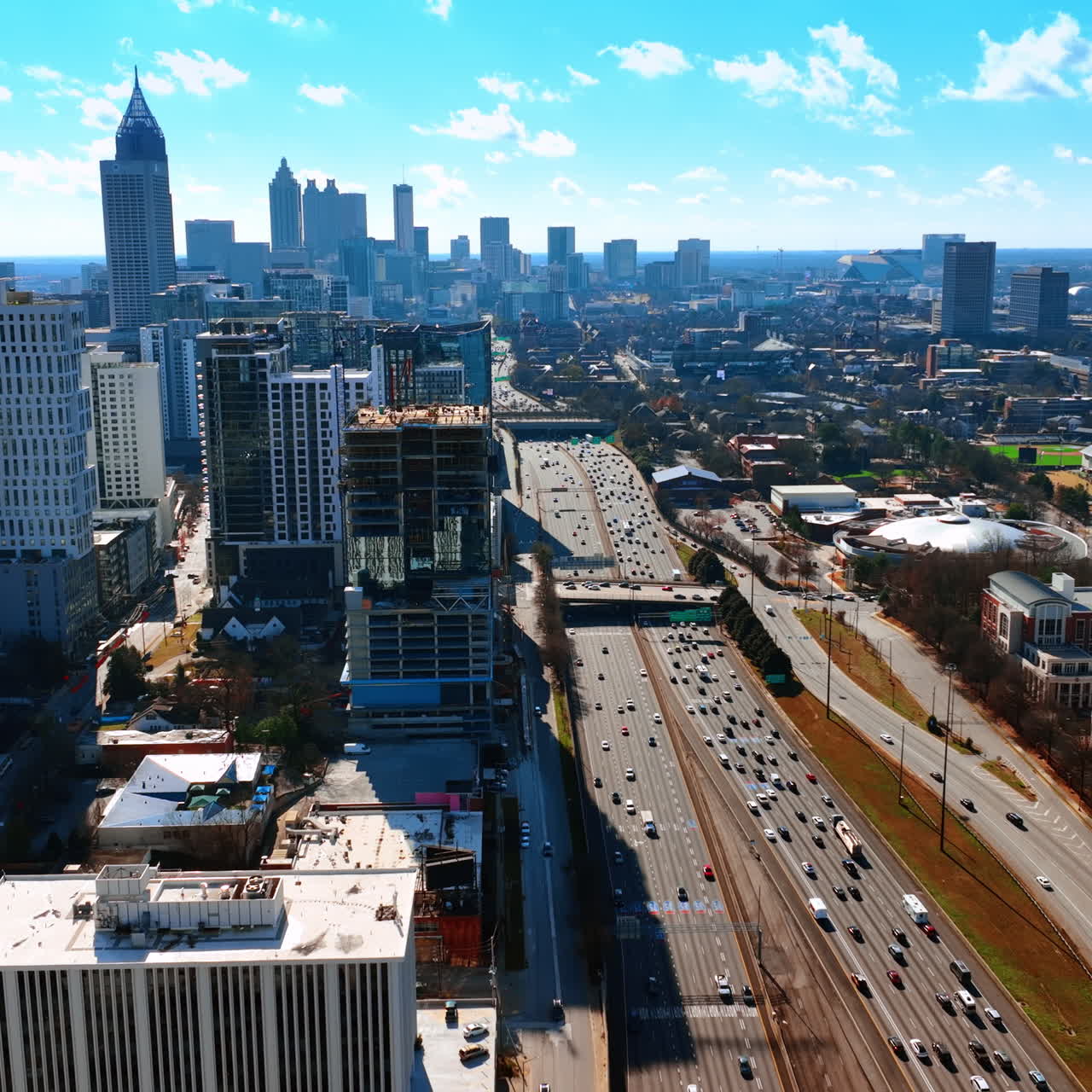 Multiple cars travel by the wide multi-lane roads of Atlanta, Georgia, USA. Sunny cityscape of busy metropolis from top view.
