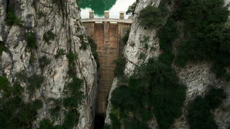 Inclinación-Aérea-Hasta-Revelación-Dramática-De-Represa-Hidroeléctrica-En-España-Durante-La-Sequía-Con-Cielo-Nublado-Y-Bajo-Nivel-De-Agua