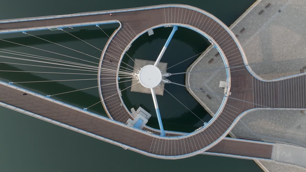 Top-down drone shot of morning joggers on a bridge in Masan Marine Park, South Korea.