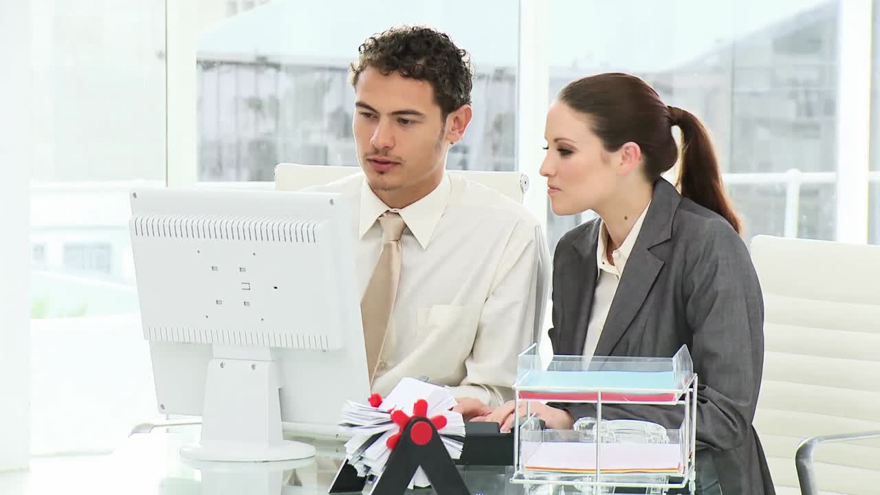 una mujer de negocios sonriente y su colega trabajando en una computadora