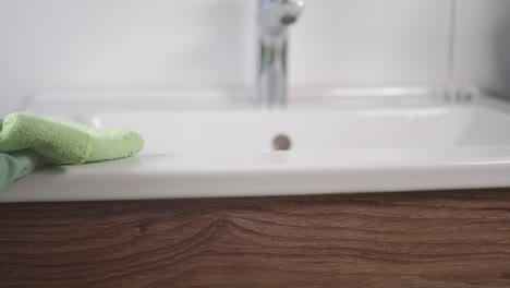 close-up of a gloved hand cleaning a bathroom sink