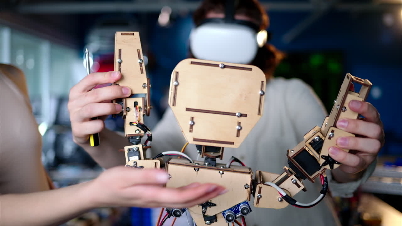 Two young engineers fixing a mechanical robot in the workshop, using VR virtual reality headsets