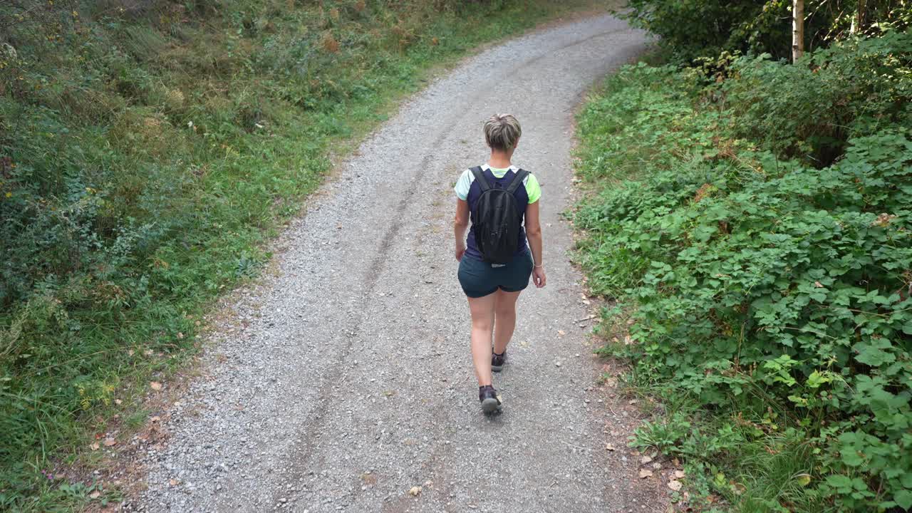 Donna che fa escursioni su un sentiero di ghiaia attraverso la foresta