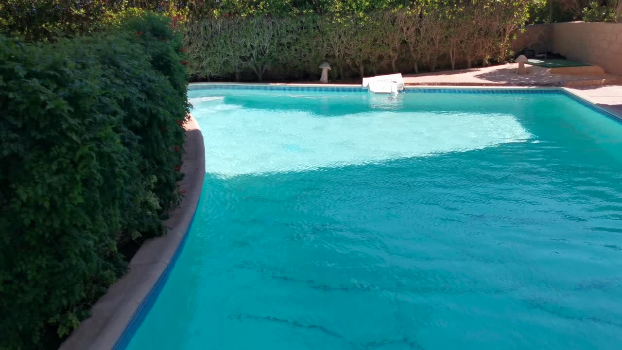 Vandoverfladetekstur, langsomme rene krusninger og bølger i swimmingpool, brydning af sollys, topudsigtstekstur, hvidt sand ved havet, solskin vandbaggrund. Baggrund med kaustiske vandeffekter