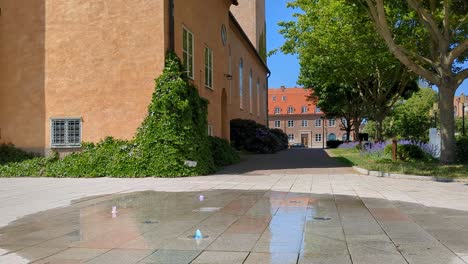 4K-60fps-Eines-Brunnens-Mit-Wasser-Außerhalb-Einer-Modernen-Kirche-In-Südschweden,-Skandinavien