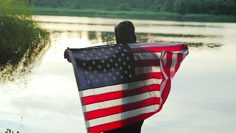 symbol of might and reflection as hooded man holds flag at river in latvia