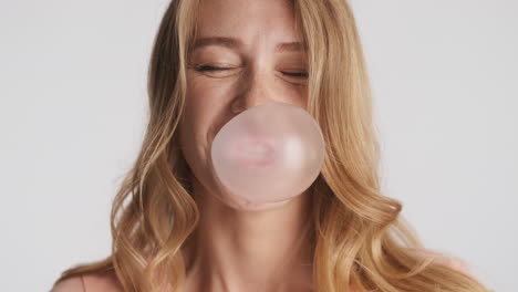 caucasian woman blowing bubblegum on camera.