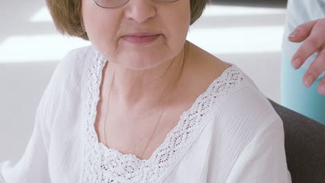 Senior-Woman-Sitting-On-A-Sofa-And-Female-Doctor-Putting-Hands-On-Her-Shoulders-2