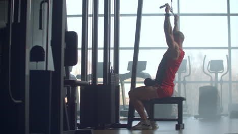 shoulder pull down machine. man working out lat pulldown training at gym. upper body strength exercise for the upper back. fit male doing cross training at gym. windows