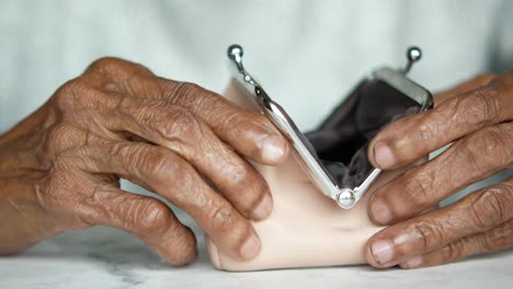 manos de ancianos sosteniendo un bolso de monedas