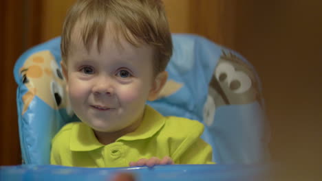 un niño encantador y sonriente sentado en la mesa de alimentación