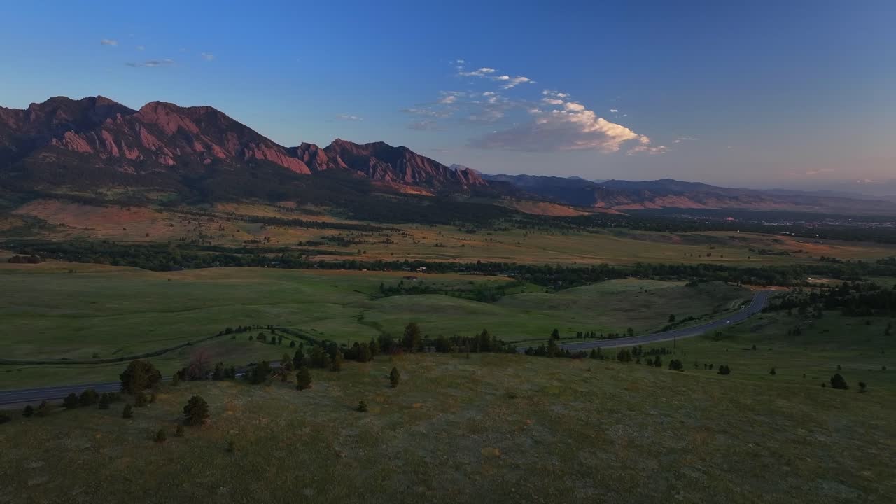 Flatirons Front Range Boulder Chautauqua Park morning sunrise aerial drone Colorado spring summer pink cloud first light on red slanted Rocky Mountains highway 36 car traffic Boulder Turnpike upwards