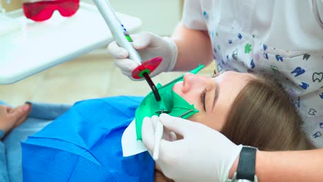 treatment and filling of a tooth with a photopolymer lamp. the girl at the dentist in white gloves