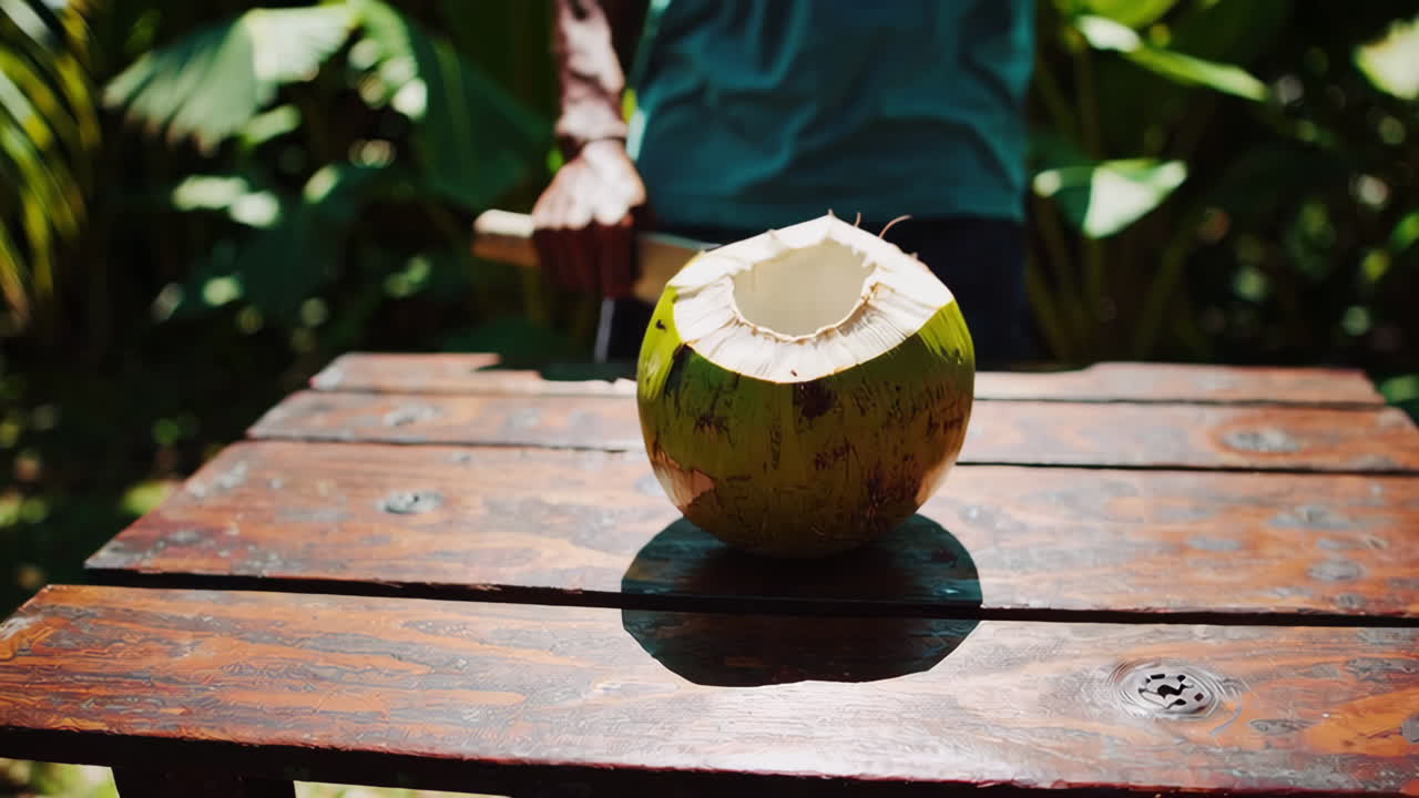 Man cutting a coconut in a tropical garden