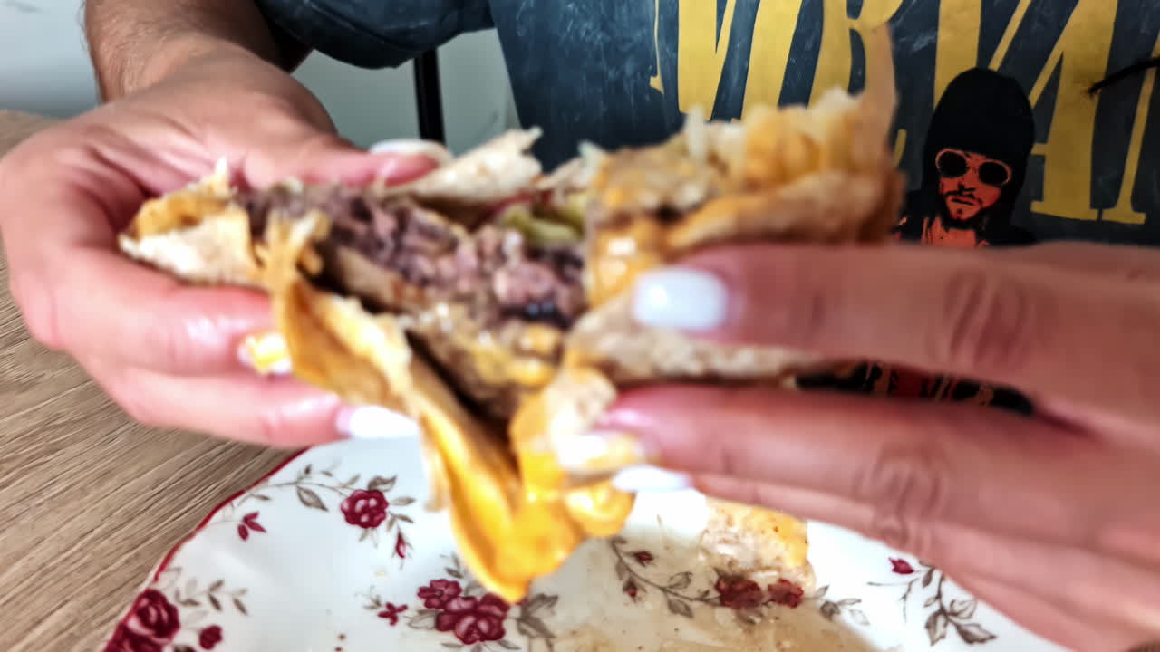 Eating messy beef taco mexican food with cheese by hand at restaurant