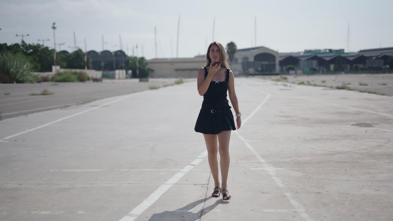 Young Woman Walking and Talking on Phone in an Empty Parking Lot