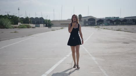 young woman walking and talking on phone in an empty parking lot